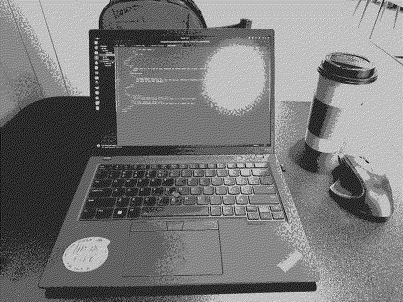 A ThinkPad sitting on a desk with a coffee cup next to it